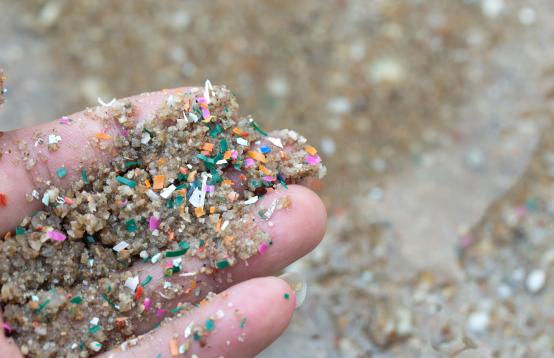 A hand holding sand dominated by micro plastics