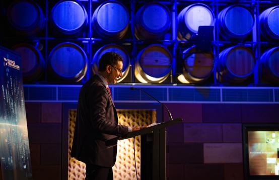 Man wearing a suit presenting from a podium