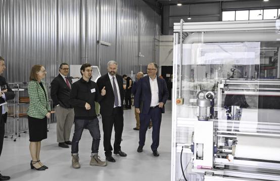 A group of people dressed in suits standing around a technical machine.