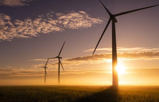 Image of a sunset with scattered clouds and windmills in the foreground.