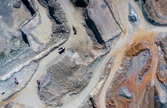 Areial view of a mining site with trucks and cars driving on the dirt roads.