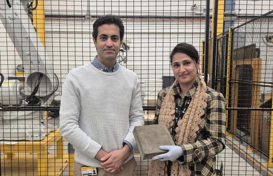 Image of two people standinf next to each other, one holding a small concrete block