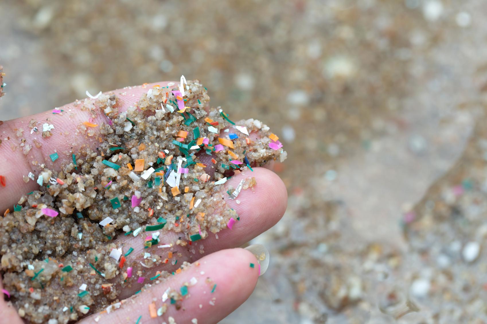 A hand holding sand dominated by micro plastics