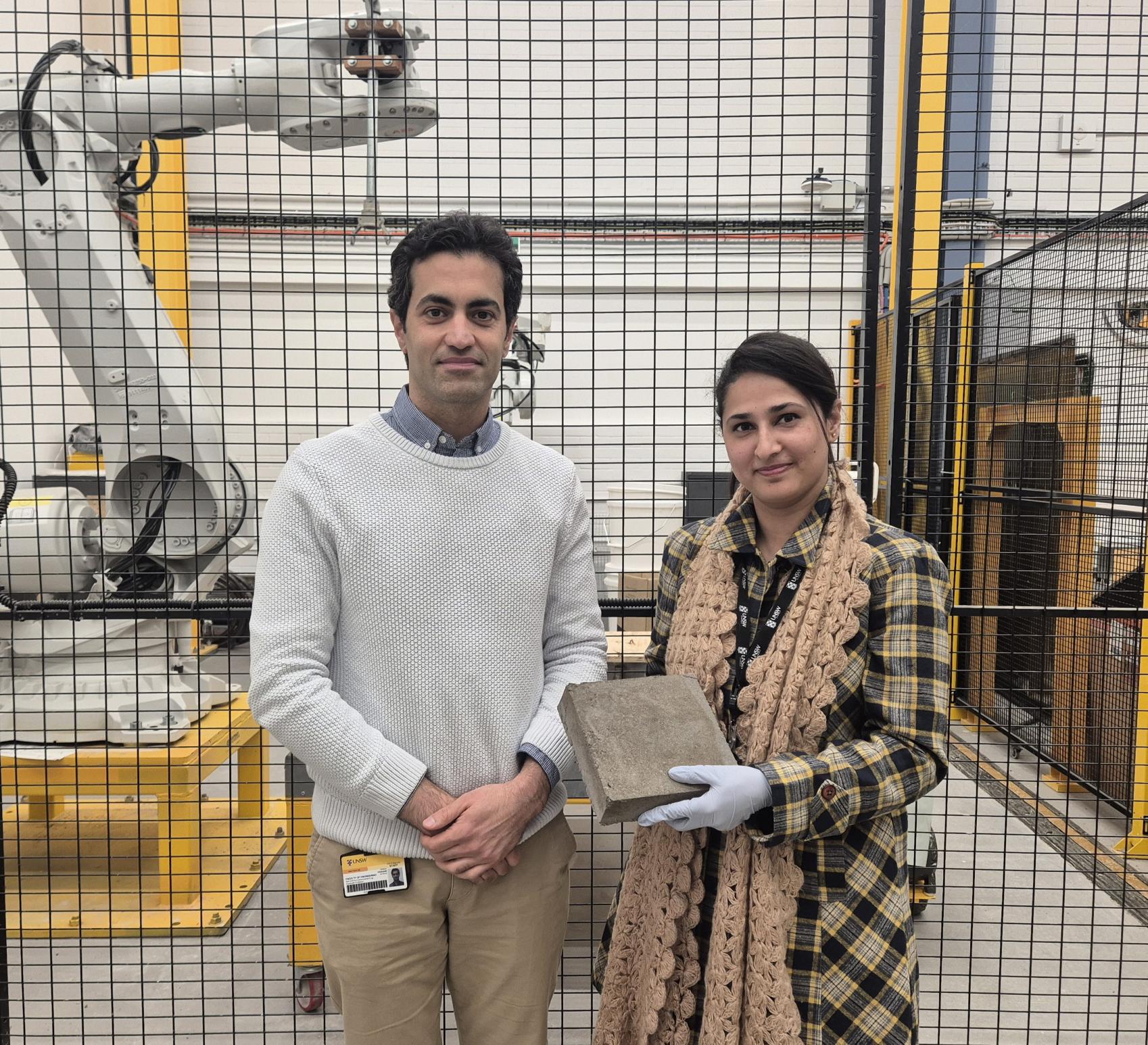 Image of two people standinf next to each other, one holding a small concrete block