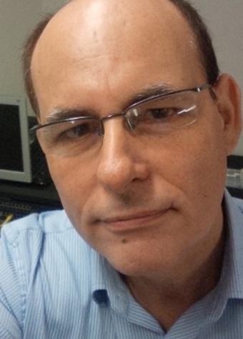 Mario Martini head shot of a man wearing glasses and a blue collared shirt